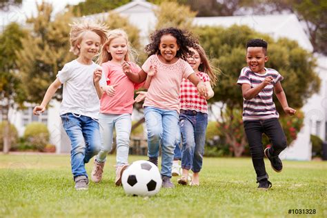 مجموعة من الأطفال يلعبون كرة القدم مع الأصدقاء في المنتزه صورة الأسهم