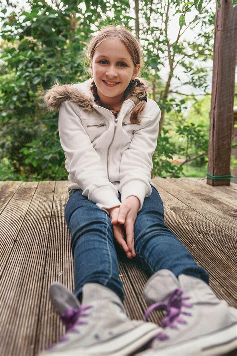 Tween Girl Sitting On A Wooden Deck Smiling To Camera By Stocksy Contributor Gillian Vann