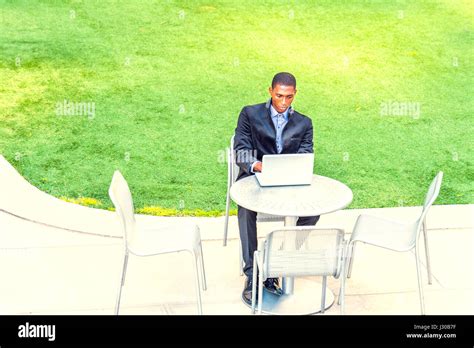 A Young Black College Student Is Sitting By Green Lawn On Campus
