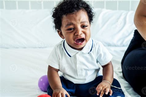 Closeup Of Adorable Little African American Baby Boy Crying On The Bed