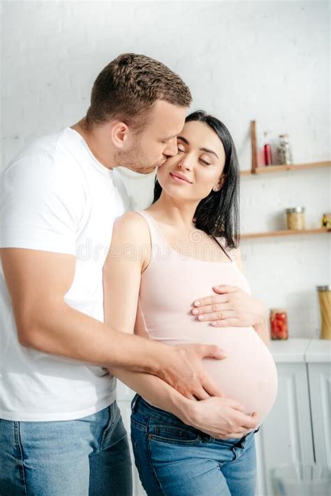 Husband Touching Belly Of Pregnant Wife And Kissing Her In Kitchen Stock Image Image Of