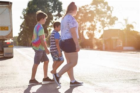 Image Of Three Kids Walking Across A Road With A Truck In The