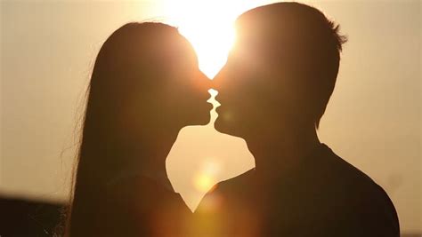 Romantic Young Couple Silhouette Is Kissing On A Sunset