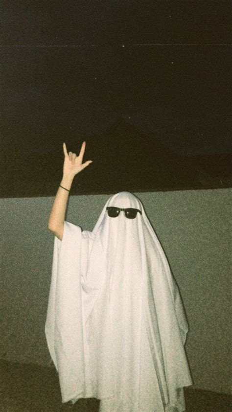 A Person In A Ghost Costume With Their Hands Up