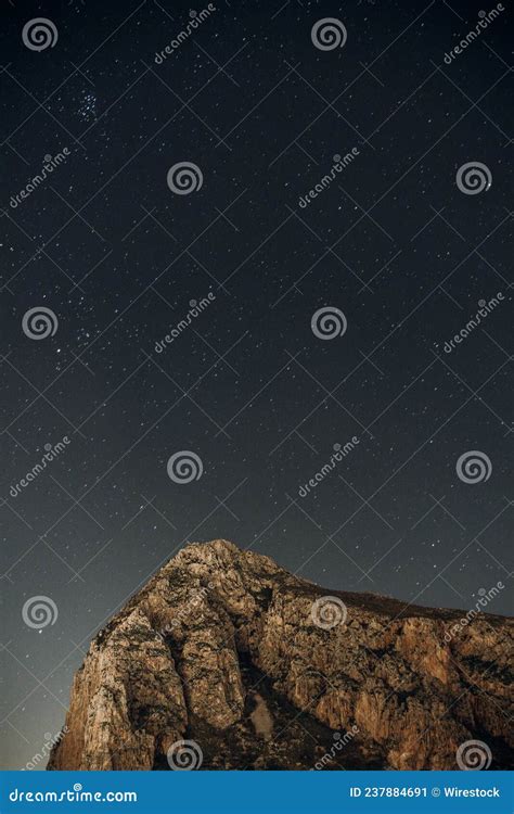 Vertical Shot Of A Rocky Landscape Under The Starry Night Sky Stock