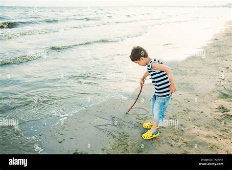 The Little Boy By The Sea Throws Stones In Water Sunset Happy