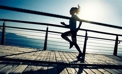 Sporty Female Jogger Morning Exercise On Seaside Boardwalk Stock Photo