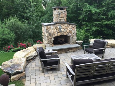 The red brick and gray stones are covered with white wash to give the finished fireplace a uniform appearance. Outdoor Fieldstone Fireplace by Landscape Solutions & Maintenance