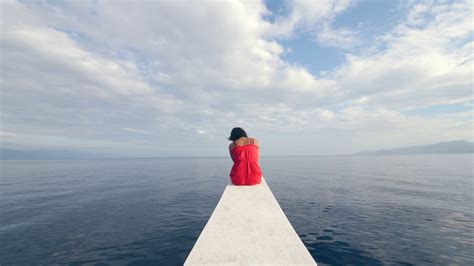 Back View Of A Sad Young Woman Sitting Alone On The Edge Of The Boat