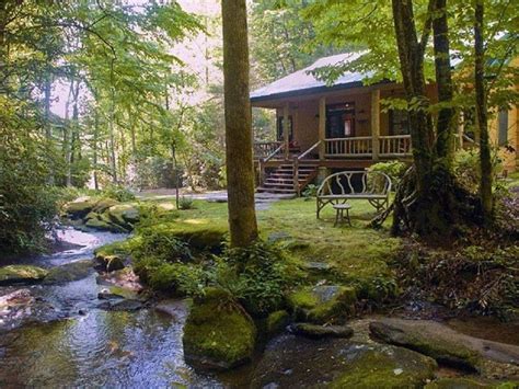 A Small Cabin In The Woods With Mossy Rocks And Water Running Through