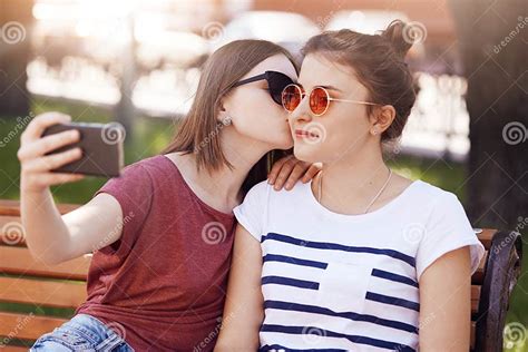 women lesbians enjoy spare time in park pose for making selfie in smart phone pretty female