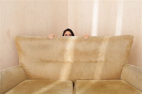 Young Woman Hiding Behind A Retro Couch By Stocksy Contributor Ulasandmerve Stocksy