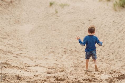 Happy Child Runs And Jumps On Sand Dunes At The Beach By Stocksy