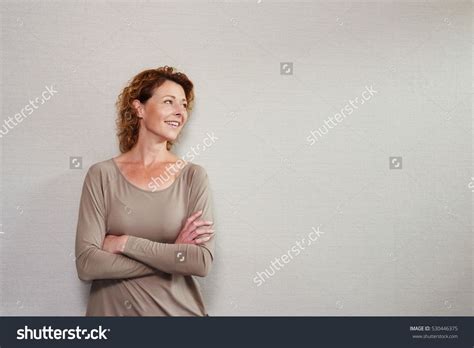Portrait Of Older Woman Standing With Arms Crossed Looking Away Smiling