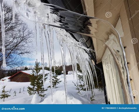 Long Clear Icicles Hanging From Roof In Winter Sunshine Stock Image