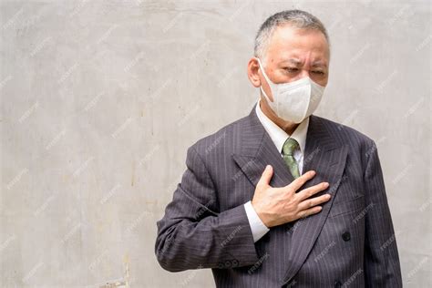 Premium Photo Stressed Mature Japanese Businessman With Mask Coughing