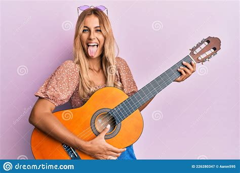 Beautiful Blonde Young Woman Playing Classical Guitar Sticking Tongue