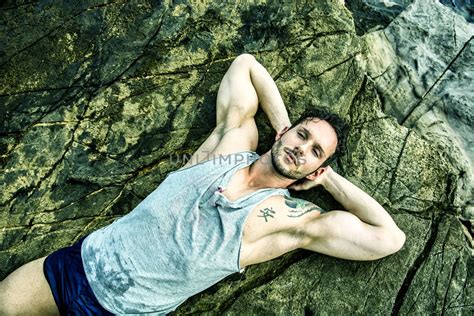 Handsome Muscular Man On The Beach Sitting On Rocks Royalty Free Stock