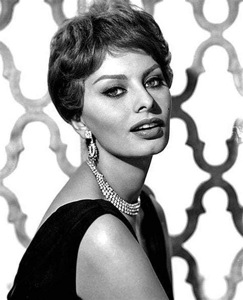 A Black And White Photo Of A Woman With Short Hair Wearing Large Necklaces