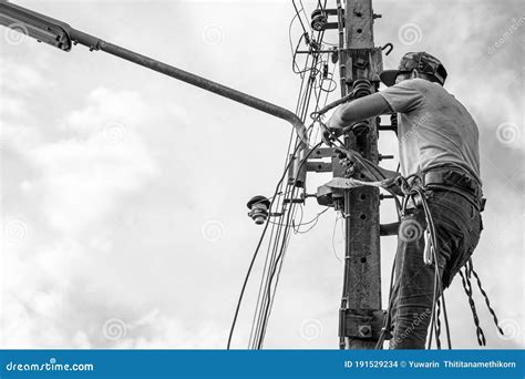 Electricians Working On Power Pole Connecting Cables With Clear Sky