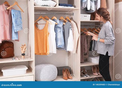 Woman Choosing Outfit From Large Wardrobe Closet With Stylish Clothes
