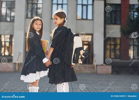 Walking Together Two Schoolgirls Is Outside Near School Building Stock