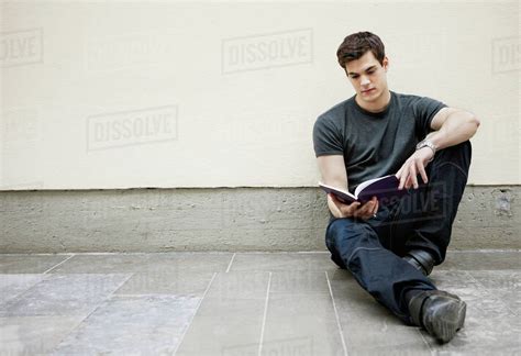 Young Man Sitting On Floor Reading A Book Stock Photo Dissolve