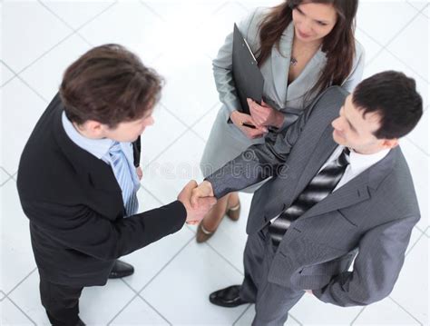 Two Business People Shaking Hands And Looking At Each Other With Stock