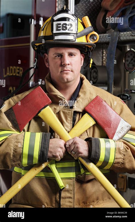 Handsome Middle Age Fireman Wearing Uniform And Fire Gear Holding Two