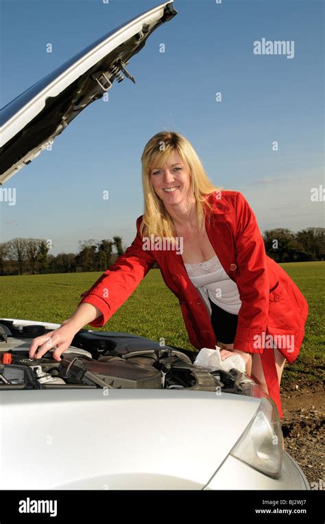 Blonde Female Motorist With The Car Bonnet Raised Checking The Oil