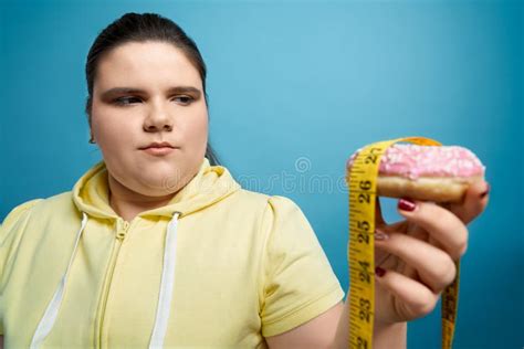 Portrait Of Fat Girl Holding Donut With Measuring Tape On It Stock