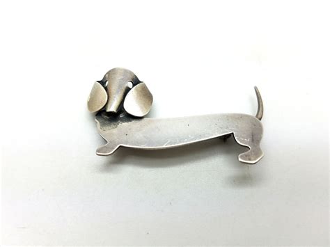 A Metal Dachshund Brooch Sitting On Top Of A White Table