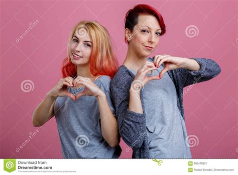 twee lesbiennes bevinden zich schouder aan schouder met handen op roze achtergrond stock