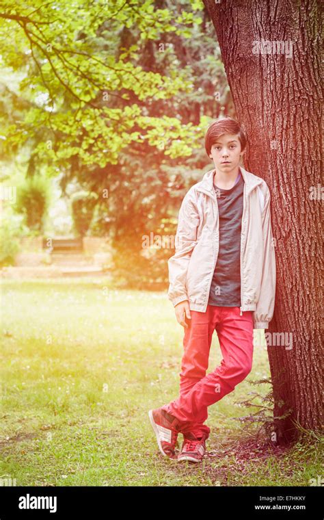 Teenager Boy Leaning Against A Tree In A Park Stock Photo Alamy