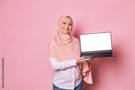 confident pregnant arab muslim woman with head covered in pink hijab smiling looking at camera