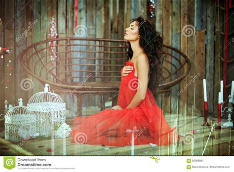 Sensual Very Beautiful Curly Girl In A Red Dress Sitting On Stock Image