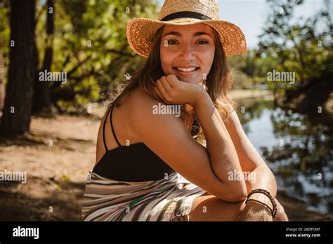 portrait of beautiful woman in bikini wearing a hat sitting by the lake female relaxing near a