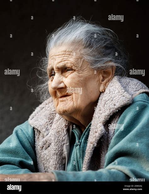 Old Woman Portrait Of A Very Old And Tired Of Life Wrinkled Woman Outdoors Near The Wall Of Her