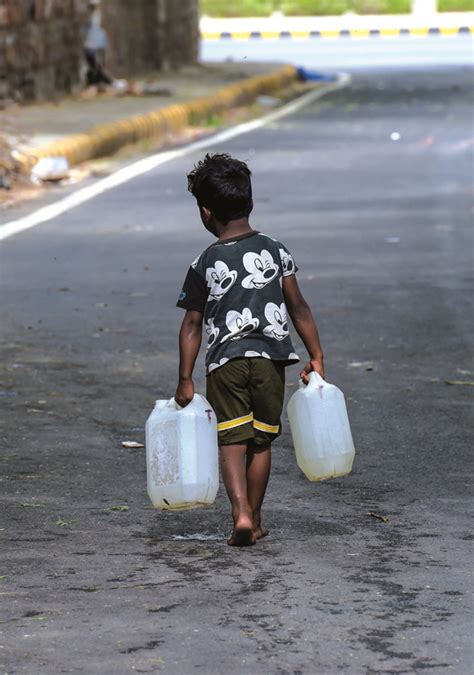 A child carries drinking water from a tanker at Vivekanand Camp amid a water crisis, in New ...
