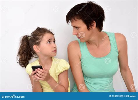 Angry Mother And Scared Daughter With Smartphone Looking At Each Other