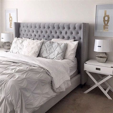 A wide, comfortable bed with gray, padded, and tufted headboard and footboard is accompanied by a white upholstered bench. bed room | Master bedroom interior design, Bedroom ...
