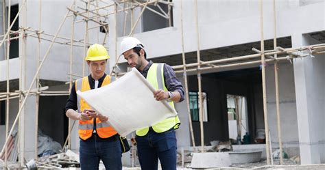 A Caucasian Male And Asian Man Civil Engineer Holding A Blueprint And