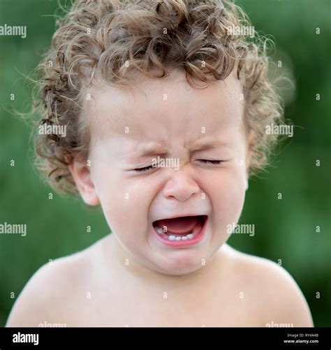 Sad Baby With Curly Hair Crying In The Garden Stock Photo Alamy