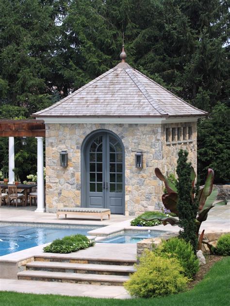 A Stone Pool House Sits Next To An Outdoor Dining Area In This