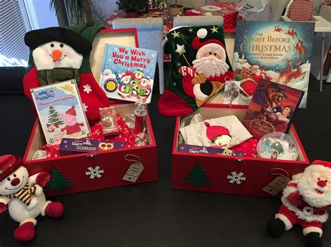 Two Red Boxes Filled With Christmas Items On Top Of A Black Table Next