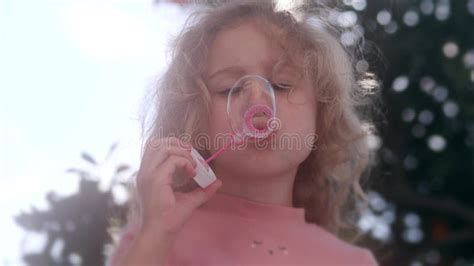 focused little blonde girl in pink blows soap bubbles stock image image of game beautiful