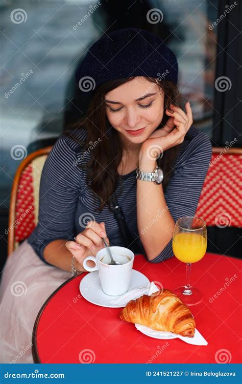beautiful elegant girl in paris sits in a parisian cafe and drinks coffee with a croissant stock