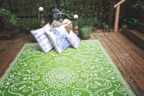 A Green Rug With White Designs On It In The Middle Of A Wooden Deck