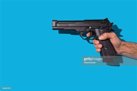 Hand Holding Gun And Aiming With Hard Shadow On Blue Background Murder