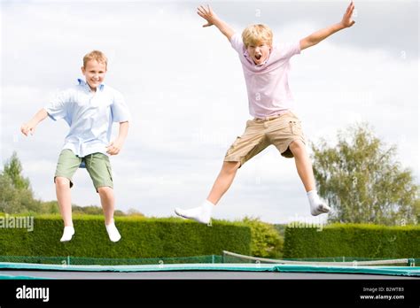 Two Young Boys Jumping On Trampoline Smiling Stock Photo Alamy